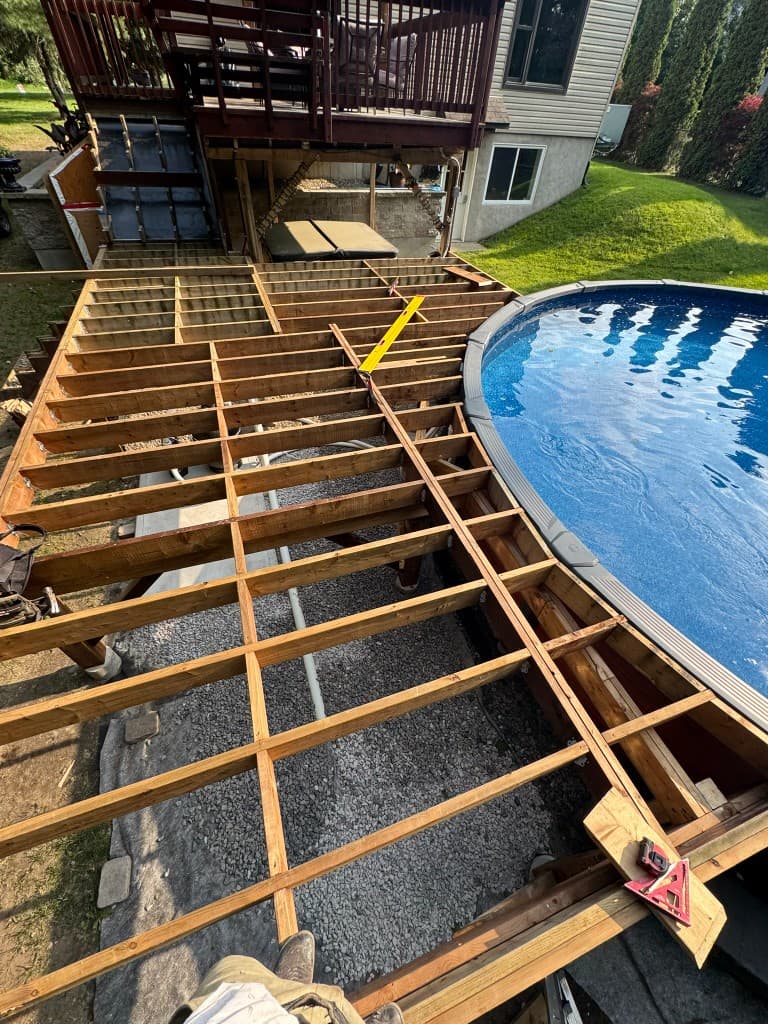 Deck framing under construction around a curved pool by Calco Construction
